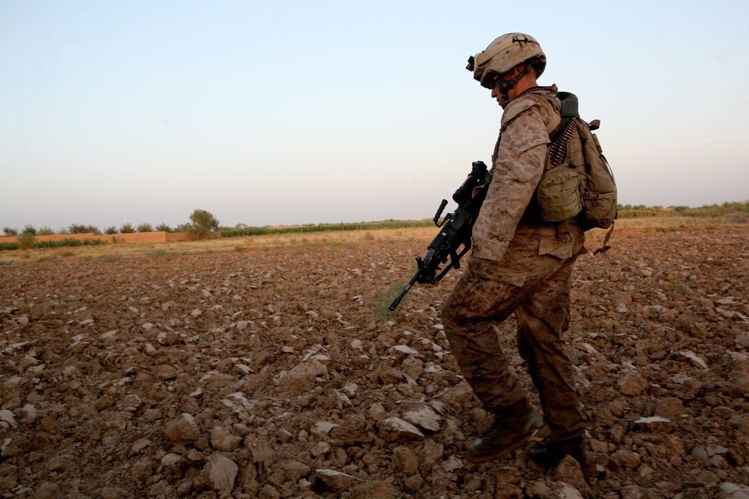 Lance Cpl. Joshua L. Hamilton, a squad automatic weapon gunner with Echo Company, 2nd Battalion, 6th Marine Regiment, patrols through open, rocky terrain during a patrol through Marjah, Afghanistan, Aug. 15, 2010. Hamilton, 25, is from Carthage, N.Y.