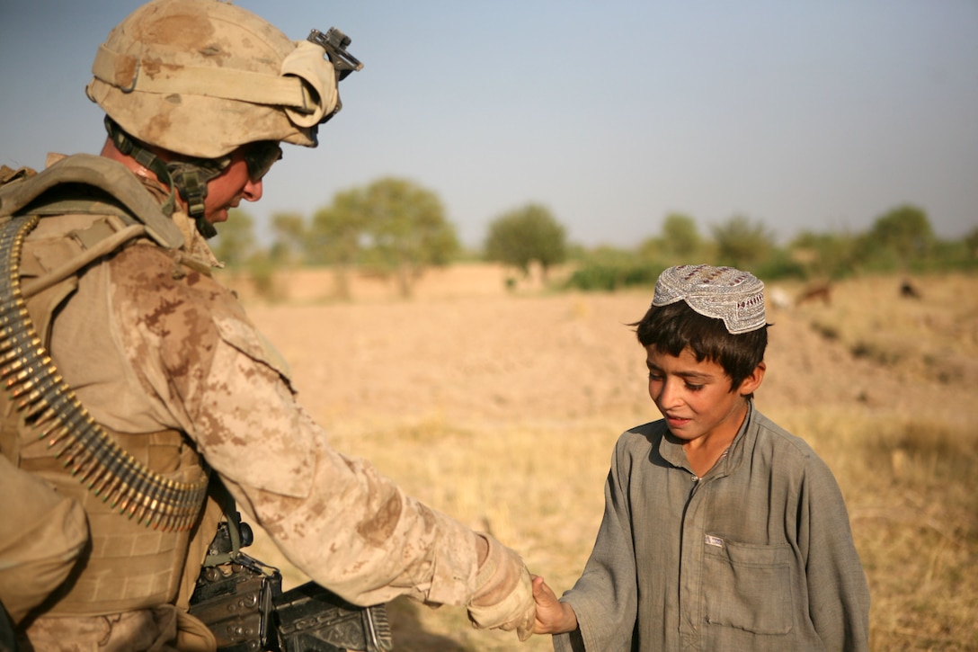 Lance Cpl. Taylor M. Boyd, a squad automatic gunner with Echo Company, 2nd Battalion, 6th Marine Regiment, shakes the hand of an Afghan boy during a patrol through Marjah, Afghanistan, Aug. 15, 2010. Boyd, 19, is from Ellenboro, N.C.