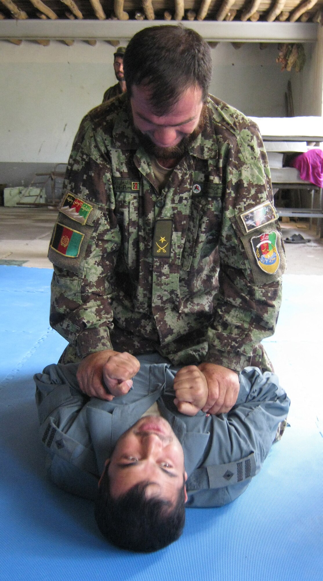 Afghan National Army Maj. Azizullah Aziz, Panjshir Operations Coordination Center-Provincial, holds down Afghan National Police Capt. Safat Ullah Sangee, OCC-P, during U.S. Army Combatives training Aug. 14 at the Panjshir OCC-P. (Photo by U.S. Air Force 2nd Lt. Jason Smith, PRT Panjshir Public Affairs)