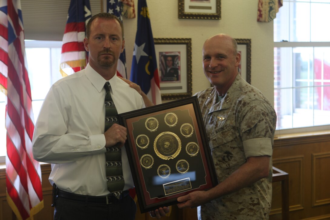 Corey Myers, safety and occupational health specialist for the Department of Public Safety aboard Marine Corps Base Camp Lejeune, receives the Award for Superior Performance from Maj. Gen. Carl B. Jensen, commanding general of Marine Corps Installations East during award ceremony on the MCIEAST commanding general's quarterdeck in Building 1 aboard the base, Aug. 16. Alongside the base's award, three Department of Public Safety personnel won awards for their contributions to base safety.