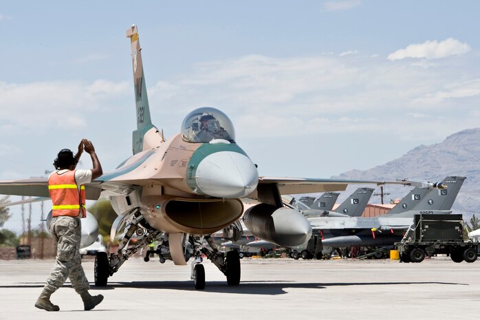 NELLIS AIR FORCE BASE, Nev.-- A crew chief from the 57th Aircraft Maintenance Squadron, Viper Aircraft Maintenance Unit marshals an F-16 assigned to the 422nd Test and Evaluation Squadron to perform a post flight end-of-runway inspection after a Green Flag West 10-9 training mission at Nellis, on August 11, 2010.  The 422 TES is training with the Royal Saudi and Pakistan Air Forces during the exercise. Green Flag-West provides a realistic air-land integration training environment for joint forces preparing to support of worldwide combat operations. (U.S. Air Force Photo by Lawrence Crespo)
