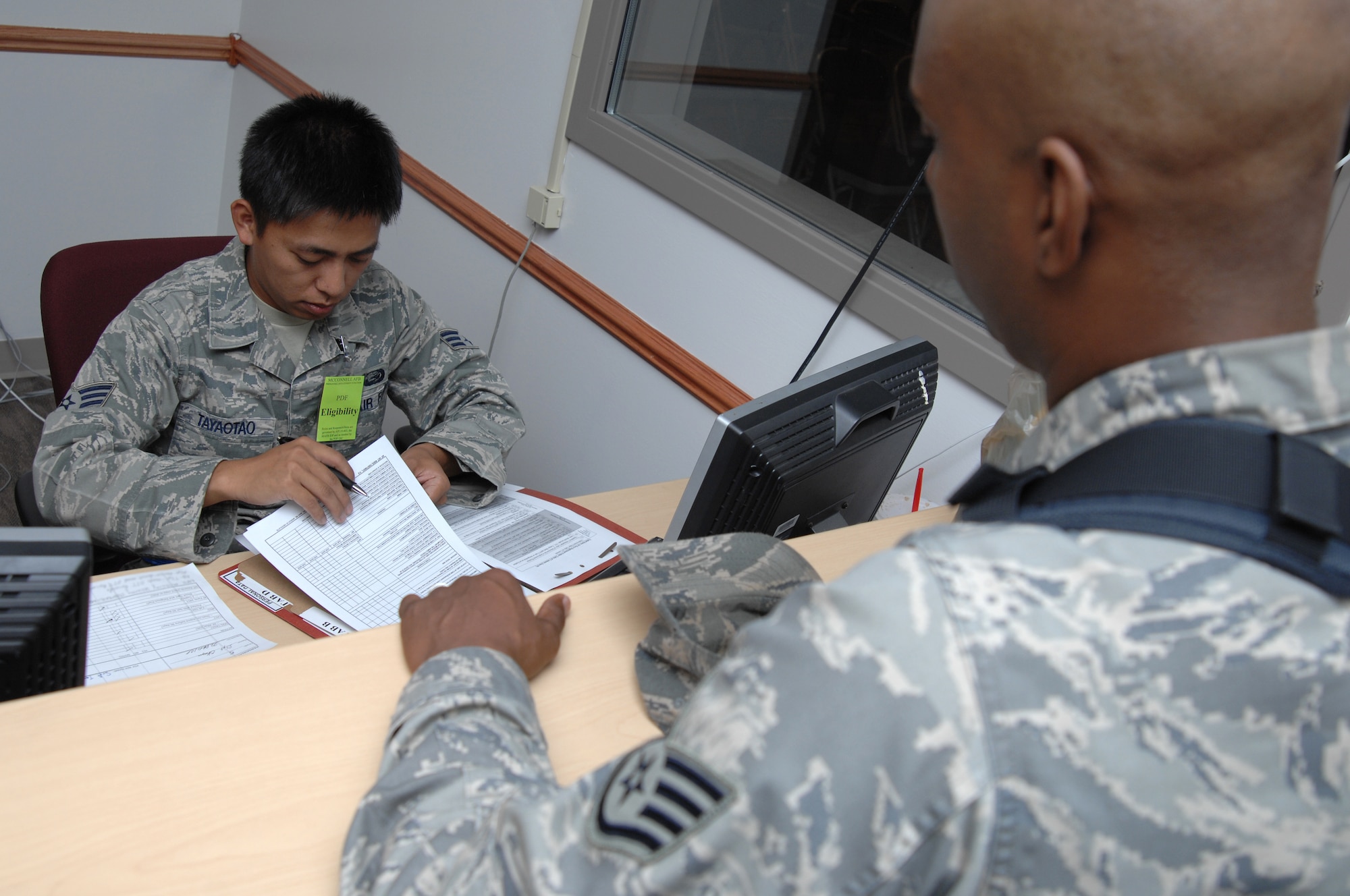 Senior Airman Henry Tayaotao, 22nd Force Support Squadron personnelist, reviews Staff Sgt. Sidney Okagu’s, 22nd Air Refueling Wing Command Post controller, mobility folder before proceeding through the personnel deployment line during an exercise, Aug. 15, 2010, McConnell Air Force Base, Kan.  The deployment line gathers specialists from different organizations around base to a central location and provides every deploying member with individual assistance ensuring all their affairs are in order prior to deployment.  (U.S. Air Force photo/Staff Sgt. Ronald Lafosse)