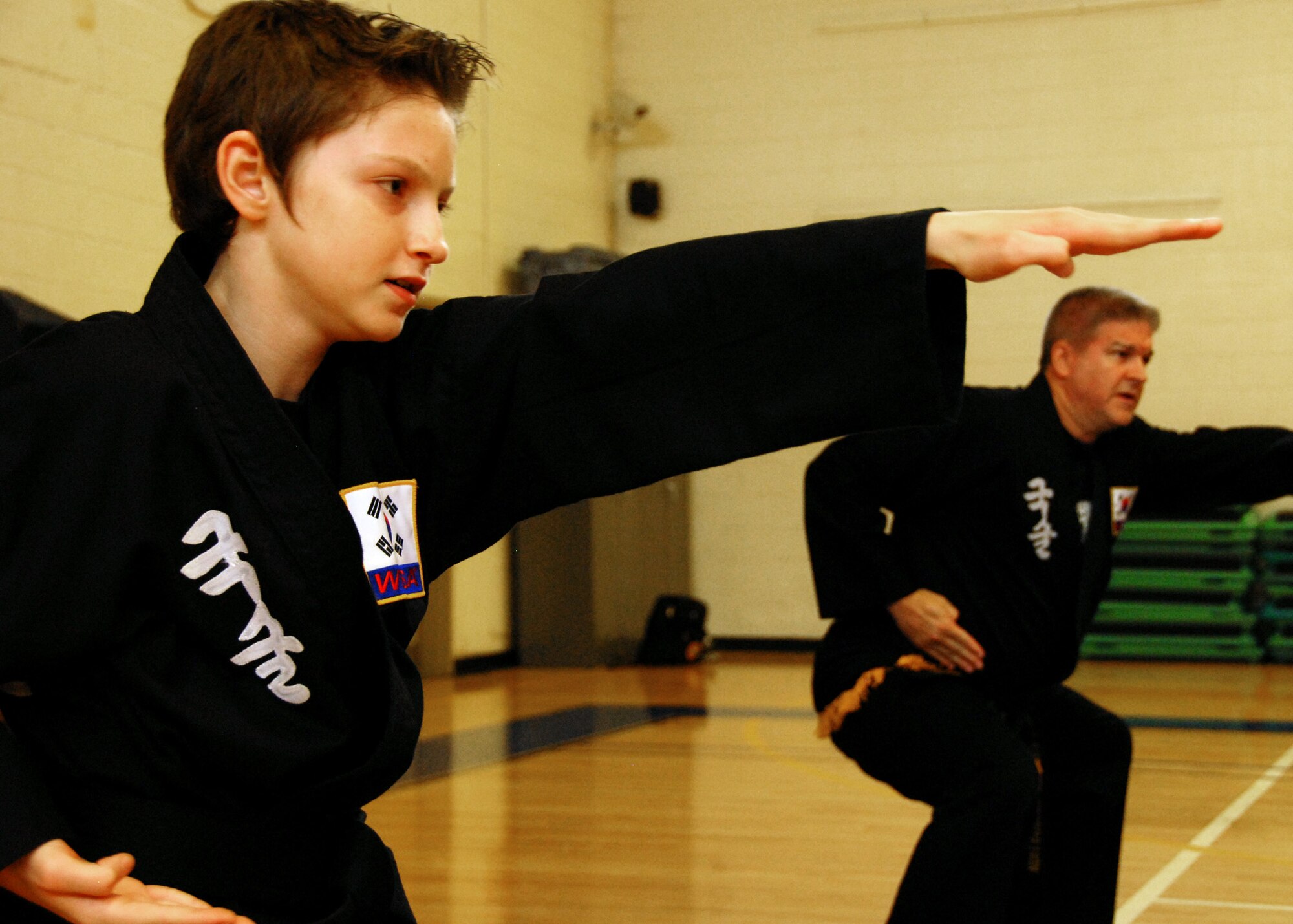 Ryan Schweitzer, assists Robert Ross with the instruction of the Kuk Sool Won class at Eglin Air Force Base, Fla.  Schweitzer, son of Master Sgt. Kevin Schweitzer, 1st Special Operations Maintenance Squadron, earned his black belt in June.  The 12-year-old has been training for four years.  Kuk Sool Won encompasses many different "styles" of traditional martial arts.  It combines kicking, punching, throwing, falling, and joint-locking as well as a myriad of weapons techniques into a dynamic 'hard-soft' style, emphasizing speed and fluidity.  (U.S. Air Force photo by Samuel King Jr.)