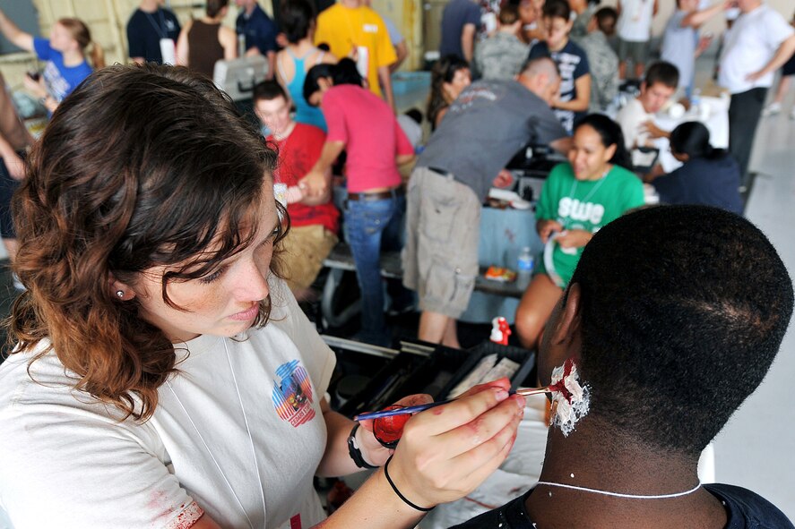 OFFUTT AIR FORCE BASE, Neb. - Volunteer Meghan Holmes applies fake wounds to the neck of Airman Jarriel Brown, 55th Intelligence Support Squadron, during a major accident response exercise August 14. Airmen with the 55th Medical Group worked with medical professionals from the surrounding Omaha metro area during a simulated aircraft accident in preperation for the Defenders of Freedom Open House and Air Show hosted here. U.S. Air Force Photo by Charles Haymond