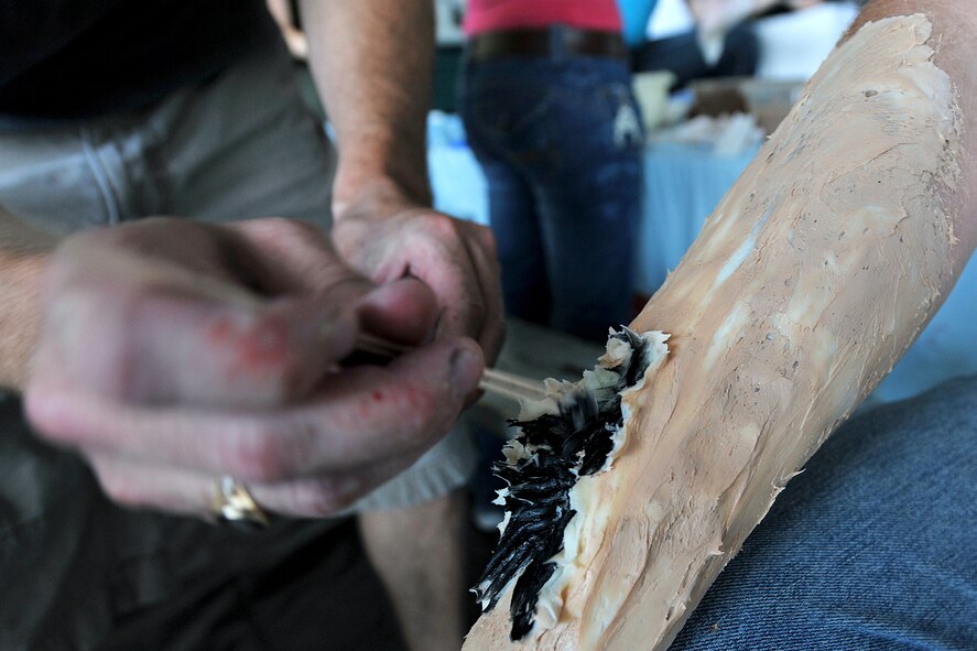 OFFUTT AIR FORCE BASE, Neb. - Tech. Sgt. Brian Madison, 55th Dental Squadron, applies make-up to Allen Straub, a volunteer, simulating an arm injuring during a major accident response exercise Aug. 14. Airmen with the 55th Medical Group worked with medical professionals from the surrounding Omaha metro area during this annual simualted aircraft accident exercise in preperation for the Defenders of Freedom Open House and Air Show hosted here. U.S. Air Force photo by Charles Haymond