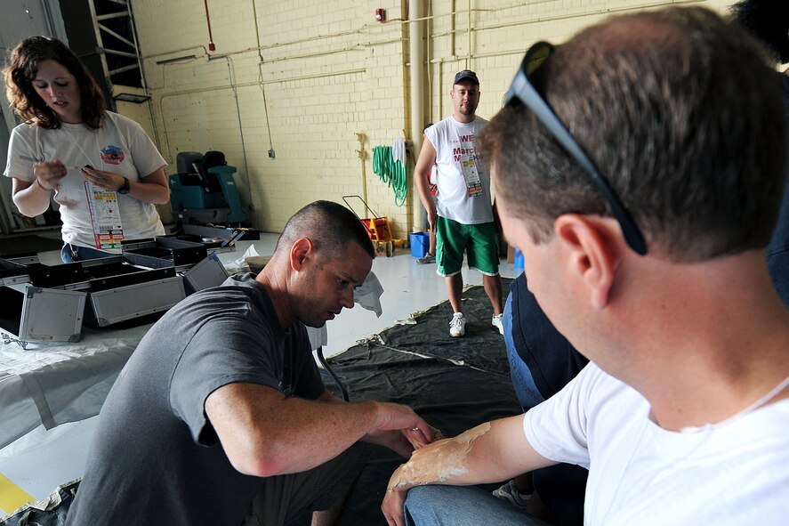 OFFUTT AIR FORCE BASE, Neb. - Tech. Sgt. Brian Madison, 55th Dental Squadron, applies make-up to Allen Straub, a volunteer, simulating an arm injuring during a major accident response exercise Aug. 14. Airmen with the 55th Medical Group worked with medical professionals from the surrounding Omaha metro area during this annual simualted aircraft accident exercise in preperation for the Defenders of Freedom Open House and Air Show hosted here. U.S. Air Force photo by Charles Haymond