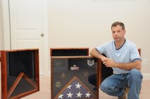 Sergeant Gary Tumminia poses next to the shadow boxes he creates. (USAF photo by SSgt. Terrica Jones, 916PA)