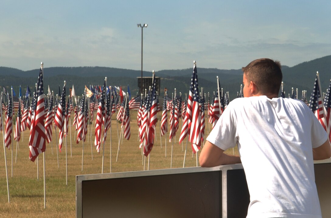 ELLSWORTH AIR FORCE, S.D. – Senior Airman Matthew Brink, 28 MXS aircraft fuel systems maintainer, looks from the Vietnam replica to the display of flags representing casualties from the current war, at the Buffalo Chip in Sturgis, S.D., Aug. 8.  Airman Brink and other volunteers helped to set up the displays.  (U.S. Air Force photo/Airman 1st Class Alessandra N. Hurley)