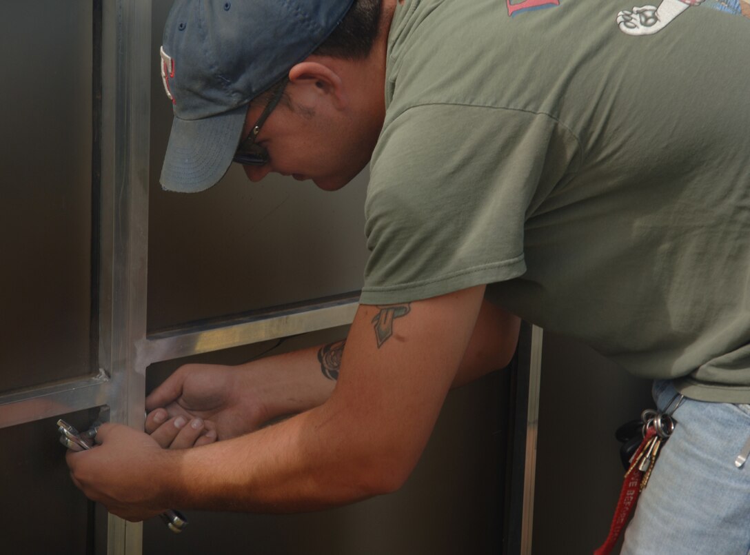 ELLSWORTH AIR FORCE, S.D. – Airman 1st Class John Weaver, 28th Maintenance Squadron aircraft fuel systems maintainer, helps to secure the panels of the traveling wall by tightening the bolts connecting them at the Buffalo Chip in Sturgis, S.D., Aug. 8.  The traveling wall honors fallen servicemembers from the Vietnam War and stands at approximately 8 feet at its tallest point.  (U.S. Air Force photo/Airman 1st Class Alessandra N. Hurley)