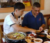 KUNSAN AIR BASE, Republic of Korea -- Master Sgt. Lim Ki-Taek, 38th Fighter Group member, explains how to eat a traditional Korean meal to Chief Master Sgt. Thomas Diaz, 8th Maintenance Group chief, during an 8th Fighter Wing and 38th FG senior NCO culture tour Aug. 10. The tour gave the Wolf Pack and Republic of Korea Air Force members the opportunity to experience Korean culture while building the U.S. and ROKAF alliance. (Republic of Korea Air Force photo/Staff Sgt. Lee Jae-Sung)
