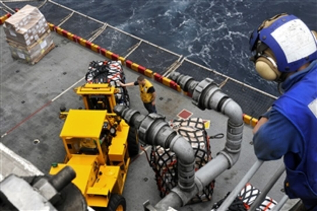 U.S. Navy Petty Officer 2nd Class Yoann Mironenko watches as sailors move supplies off the portside elevator aboard the USS Peleliu during a vertical replenishment with the USNS Lewis and Clark in the North Arabian Sea, Aug. 14, 2010. The Peleliu Amphibious Ready Group is supporting the Pakistani government and military disaster relief efforts with heavy-lift capabilities in flooded regions of Pakistan.