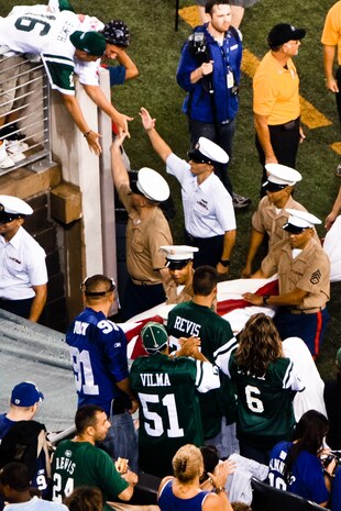 Marines, Sailors, Coast Guardsmen, Airmen and Soldiers trade high fives with fans while marching off the field after unfurling an American Flag across the field for a pre-game ceremony before the New York Jets vs New York Giants game, Aug. 16, East Rutherford, N.J. The game was the first football game in New Meadowlands Stadium, the newly built home of both New York football teams. (Official Marine Corps photo by Sgt. Randall A. Clinton / RELEASED)