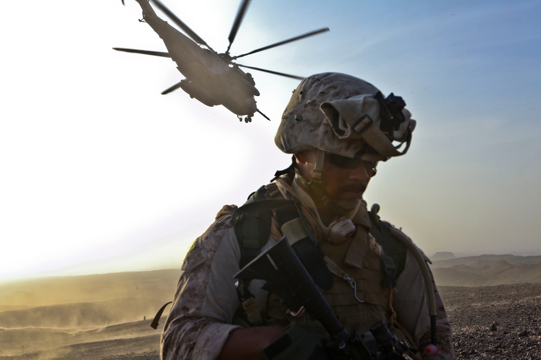 Petty Officer 3rd Class Donte Veals, a corpsman with the 1st Marine Division (Forward)'s Personal Security Detachment, provides security at helicopter landing zone Barton as a CH-53E Super Stallion from Marine Heavy Helicopter Squadron 361, 3rd Marine Aircraft Wing (Fwd), takes off, Aug. 16. HMH-361 transported Veals, 16 Marines and six geologists to the remote area in support of Operation Centrum so they could gather rock samples in search of rare valuable earth elements. The mountainous terrain made the area inaccessible by vehicle, and having a close HLZ and heavy-lifting helos allowed the group to remove almost 200 pounds of samples for further testing.