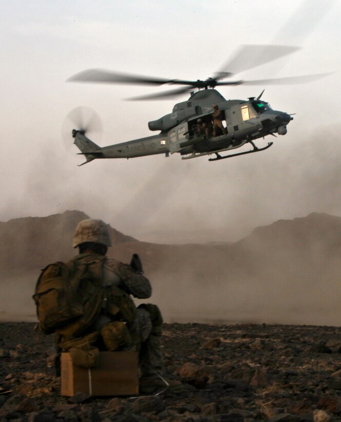 A Marine with the 1st Marine Division (Forward)'s Personal Security Detachment watches as a UH-1Y Huey from Marine Light Attack Helicopter Squadron 369, 3rd Marine Aircraft Wing (Fwd), lands to deliver water to the PSD and six geologists Aug. 16 in support of Operation Centrum. The team was awaiting extraction by Marine Heavy Helicopter Squadron 361, 3rd MAW (Fwd) when the Huey pilots offered to drop extra water to the group. HMH-361 inserted the group about 12 hours earlier that day so the team could search for rare earth elements.