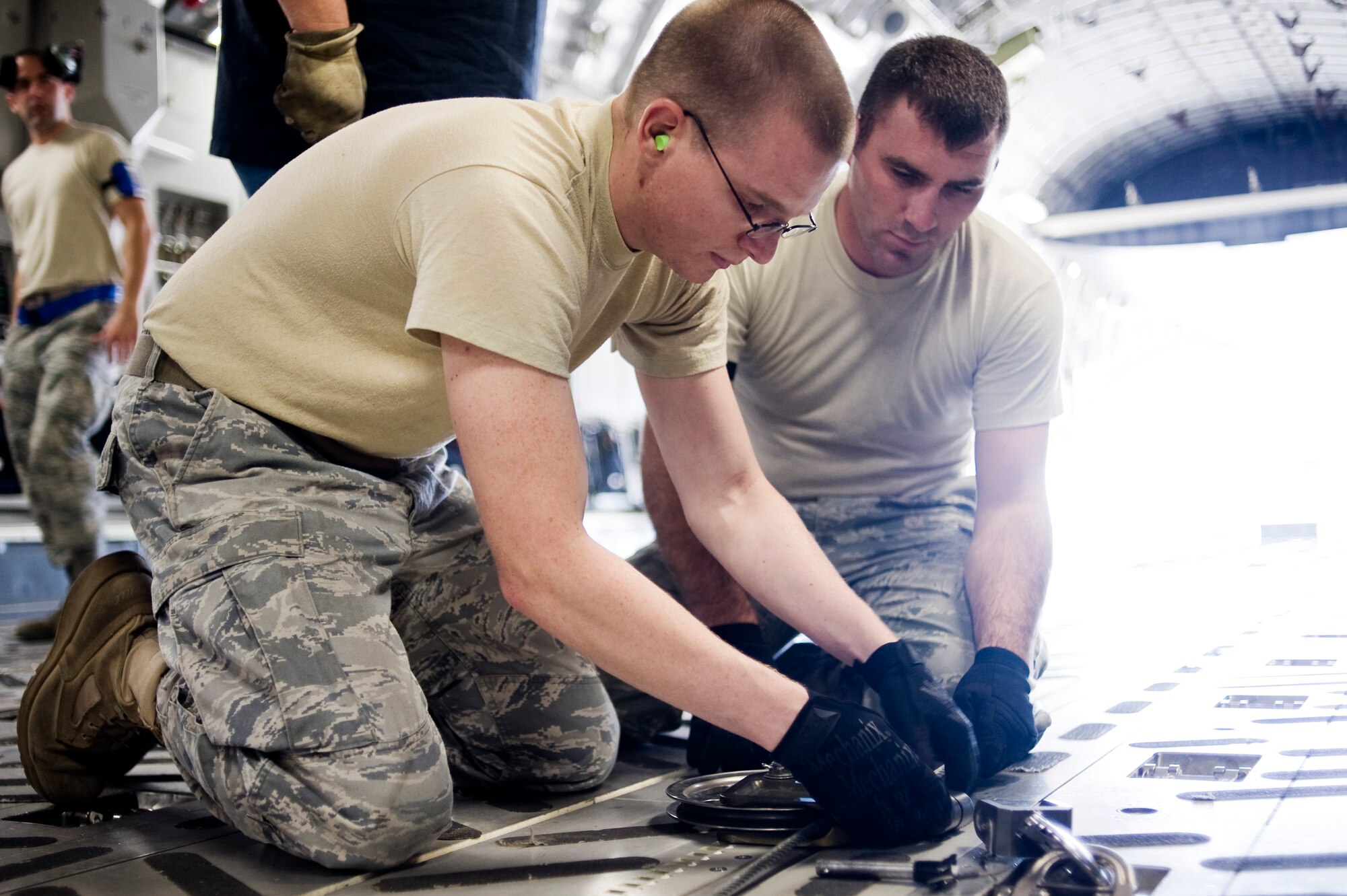 Senior Airman Jeremy Schmid, left, and Staff Sgt. Ryan Stoks, assigned to the 62nd Aerial Port Squadron, Joint Base Lewis-McChord, Wash., attach snatch blocks to a powered winch onboard a C-17 Globemaster III to redirect the cable during Aerial Port Expeditor training Aug. 17 at Joint Base Lewis- McChord, Wash. (U.S. Air Force photo/Abner Guzman)


