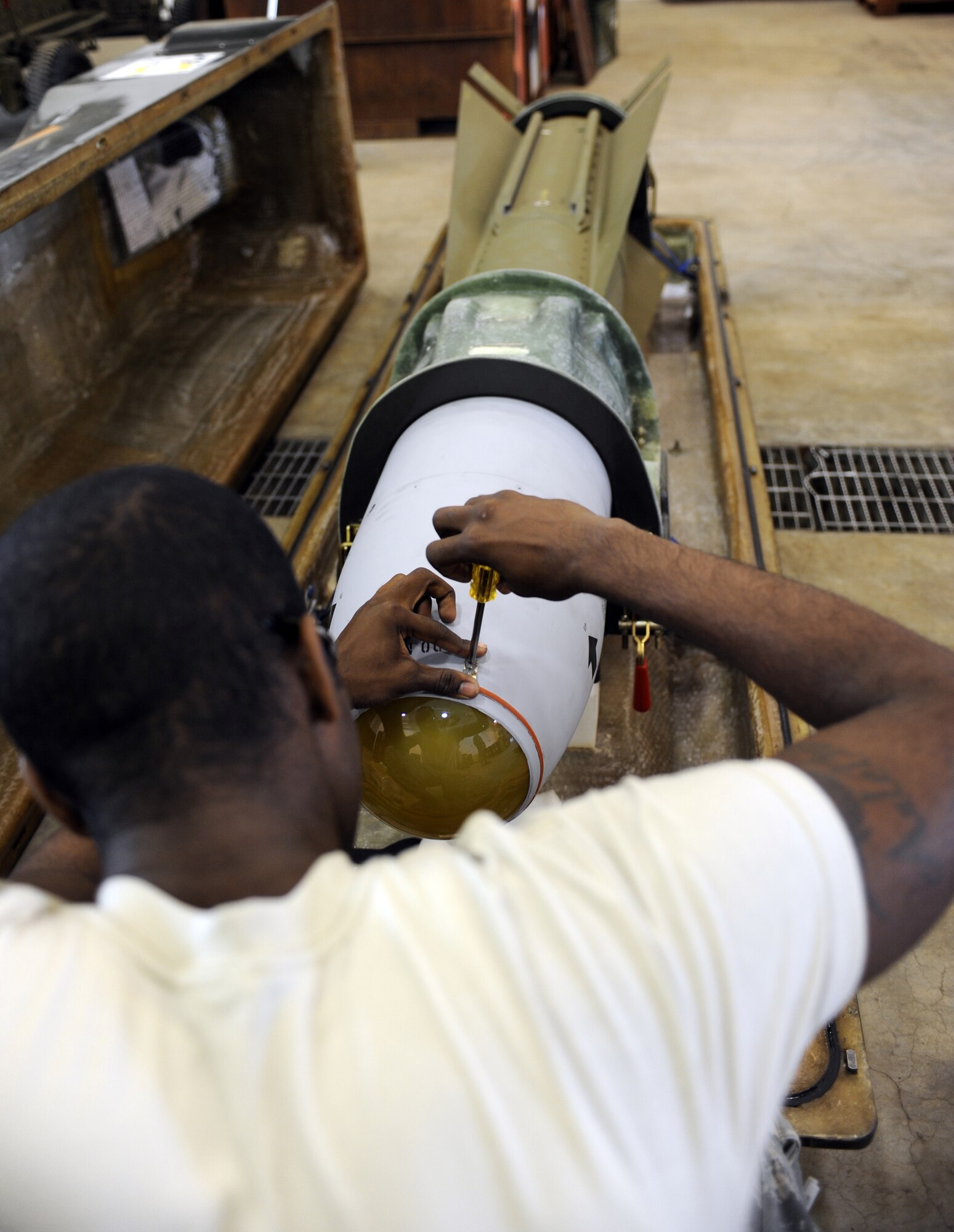 Senior Airman Clarence Burse removes a protective dome cover from an AGM(Air to Ground)-65 missile August 13, 2010, Eielson Air Force Base, Alaska.  In training environments these covers are removed before flight for safety purposes. Pilots fire these missiles at simulated or real armored targets on Eielson's ranges. Airman Burse is a Precision Guided Munitions Crew Chief stationed at Osan Air Base, Korea. (U.S. Air Force photo/Senior Airman Willard E. Grande II)