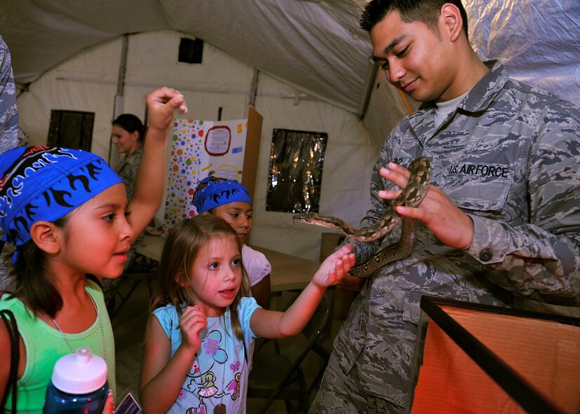HOLLOMAN AIR FORCE BASE, N.M. -- Inez Cordova, daughter of Staff Sgt. Gilbert Cordova, 49th Logistics and Readiness Squadron and Brooklyn Wickersham, daughter of Staff Sgt. Samual Wickersham, 49th LRS, check out a Dumeril Boa snake with Airman 1st Class Antonio Cruz, 49th Aeromedical Dental Squadron, during Operation K.I.D.: Kids Investigating Deployment, Aug. 12, 2010. A display set up by the 49th AMDS, Public Health Element, showed Holloman children different critters that could be found in a deployed location. (U.S. Air Force photo by Senior Airman Veronica Stamps / Released) 
