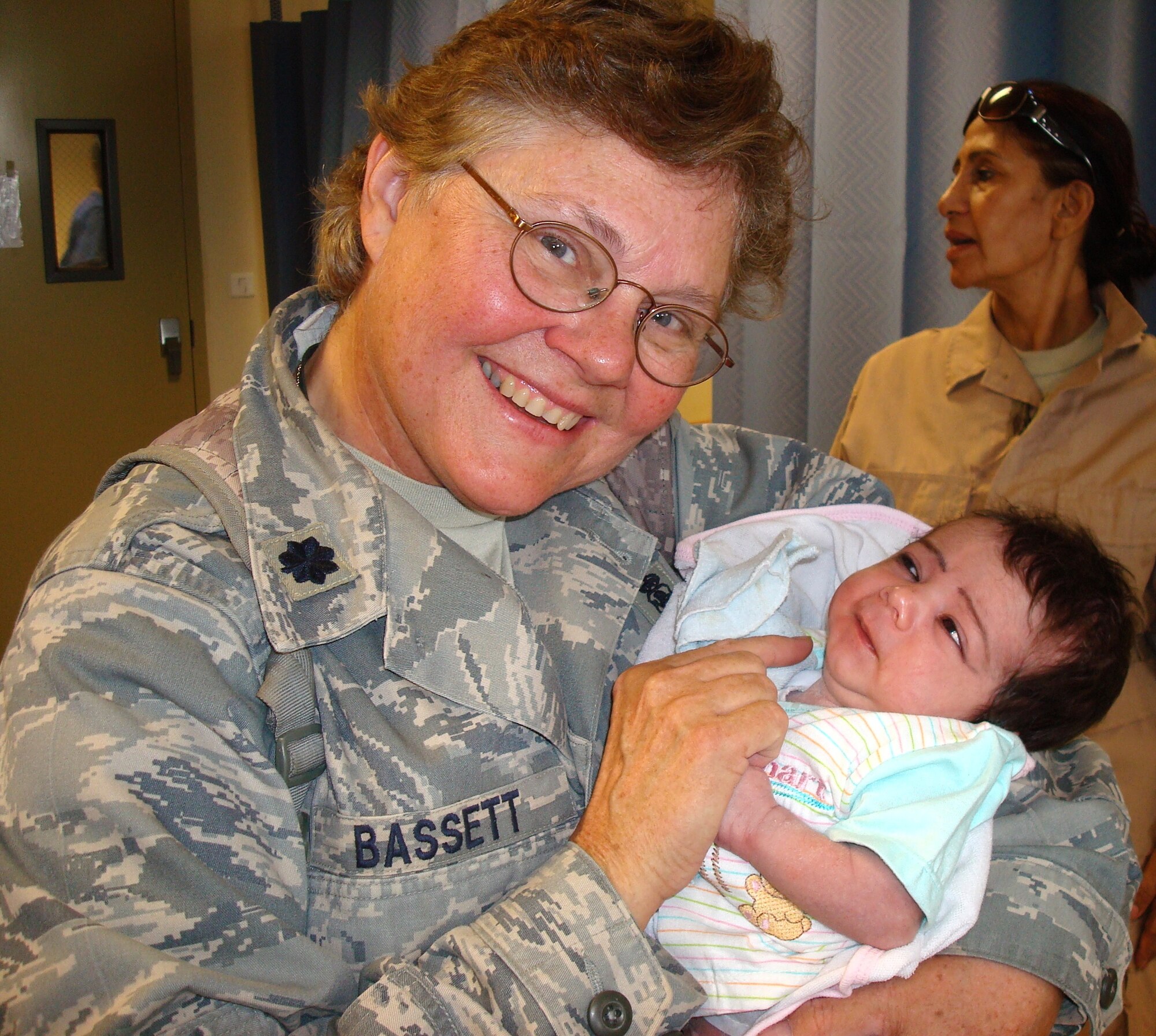 Colonel Bassett holds a baby during the weekly women’s clinic. She explained, “We had one Afghan midwife, an Afghan Army major, who was brought secretly from her home to help see the female patients.  Only female staff members were permitted to see women and their children.”  (Courtesy photo)
