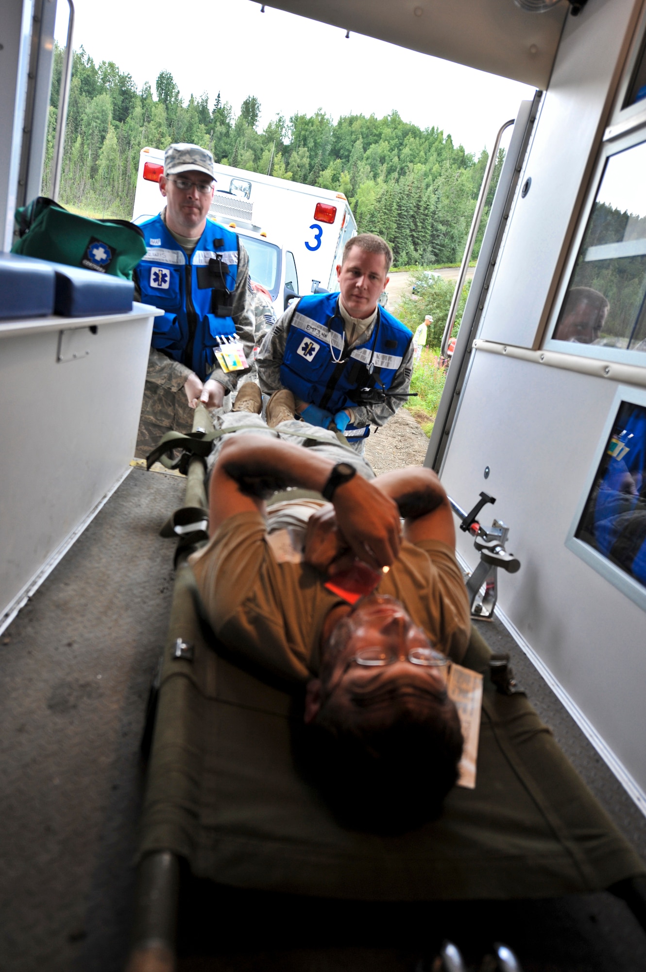 JOINT BASE ELMENDORF-RICHARDSON, Alaska – Participants of the Expeditionary Medical Support Training load a “patient”, into the back of an ambulance during a simulated bridge collapse scenario, Aug. 12. The five-day EMED training was held for the first time at Joint Base Elmendorf-Richardson, Aug. 9-13. Eighty-one Airmen from around the Pacific Air Forces came to the mandatory pre-deployment training. The EMEDs training is typically held at Brooks City Base in San Antonio. (Air Force photo by Airman 1st Class Christopher Gross)