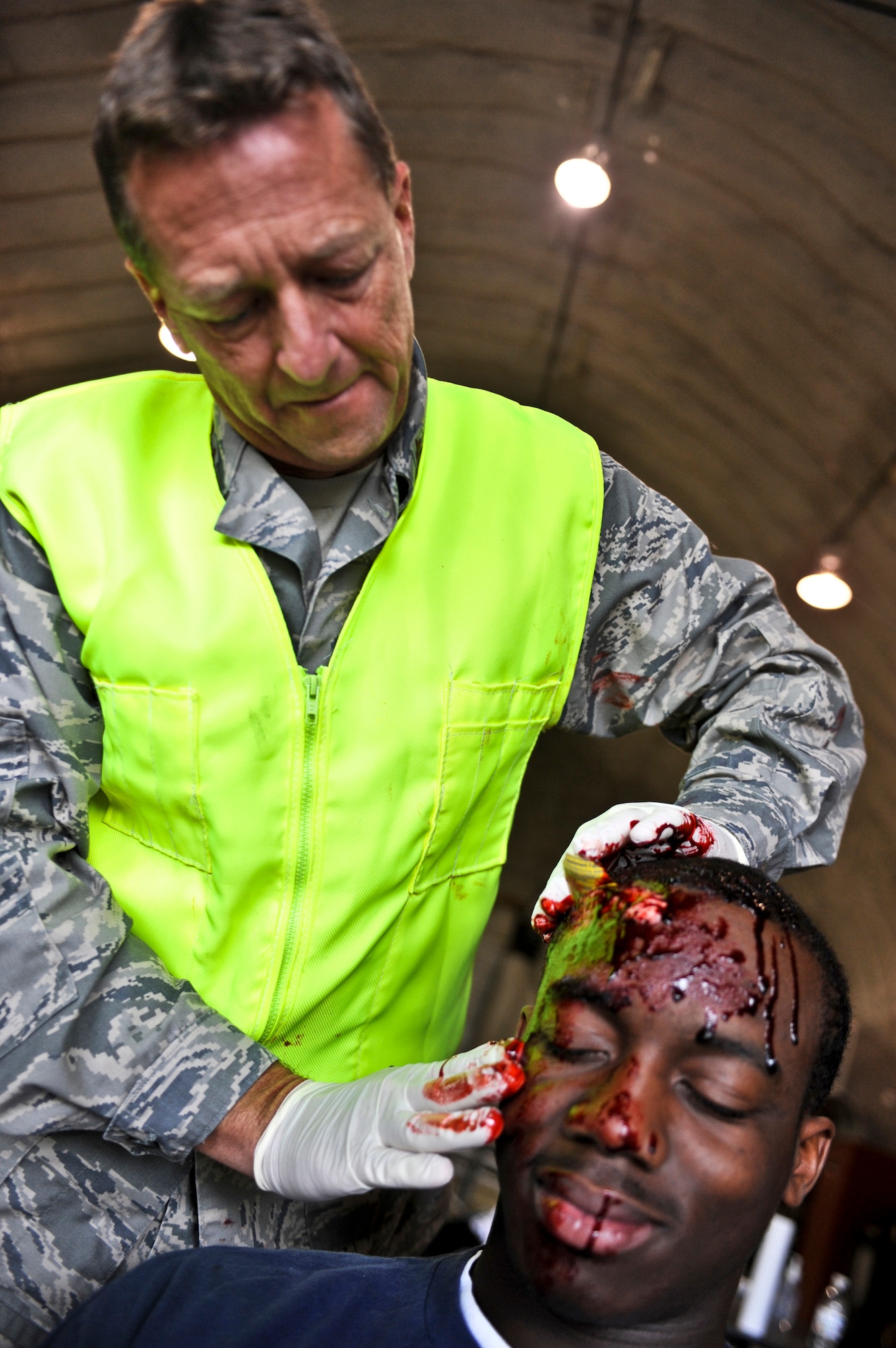 JOINT BASE ELMENDORF-RICHARDSON, Alaska – Maj. Steven Keifer, Brooks City Base, San Antonio, applies makeup and mock shrapnel to the head of Brendon Rhoden, a “patient,” Aug. 12. The five-day Expeditionary Medical Support Training was held for the first time at Joint Base Elmendorf-Richardson, Aug. 9-13. Eighty-one Airmen from around the Pacific Air Forces came to the mandatory pre-deployment training. The EMEDs training is typically held at Brooks City Base in San Antonio. (Air Force photo by Airman 1st Class Christopher Gross)