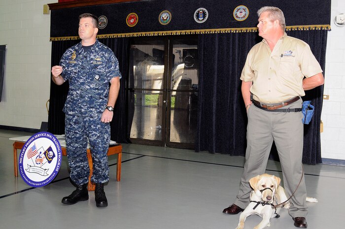 Commanding Officer Navy Cmdr. Ray Drake, left, along with Rick Hairston, president and CEO of Carolina Canines for Veterans, announced that the program expects to begin with seven canines arriving Aug. 31. Since the program's inception in 1996, 10 dogs valued at more than $400,000 have been placed with wounded warriors, allowing disabled veterans more independence. (U.S. Navy photo/Mass Communication Specialist 1st Class Jennifer Hudson)
