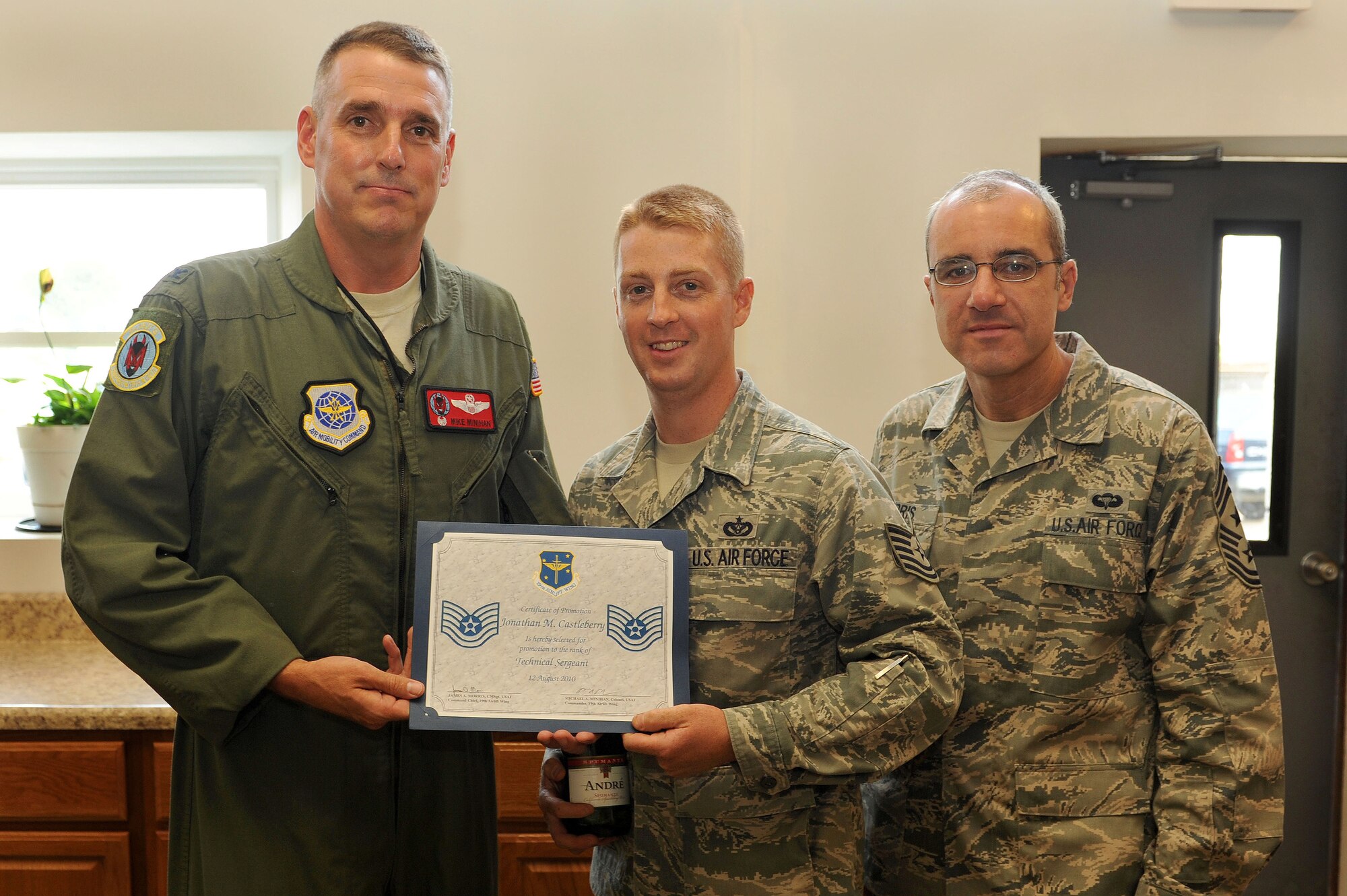 Col. Mike Minihan, 19th Airlift Wing commander; and Chief Master Sgt. James Morris, 19th Airlift Wing command chief; present a certificate of promotion Aug. 12 to Tech. Sgt. Jonathan Castleberry, 19th Civil Engineer Squadron structural craftsman. Sergeant Castleberry was surprised on his lunch break with an extra stripe “tacked” on by wing leaders as well as his civil engineer peers for being Stripes for Exceptional Performers promoted. He recently returned from a deployment to Iraq where he was lauded for his joint training leadership and efforts in reconstruction of an existing flightline. (U.S. Air Force photo by Senior Airman Steele C. G. Britton)