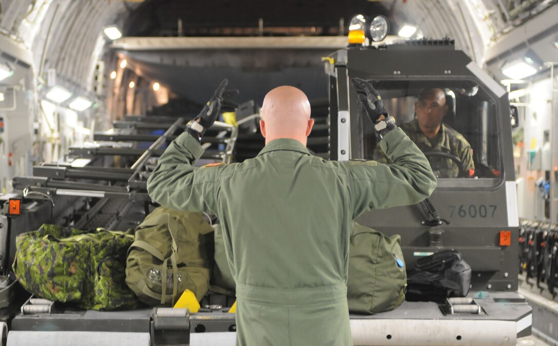 Staff Sgt. James Grove, a reservist and loadmaster with the 326th Airlift Squadron at Dover Air Force Base, Del., marshals in a Halverson K-loader at 8 Wing at Canadian Forces Base, Trenton, Ontario, Aug. 13, 2010. The C-17 aircrew delivered the piece of equipment to Thule Air Base, Greenland, as part of the Canadian Operation BOXTOP, conducted each spring and fall. Supplies are staged at Thule AB and Canadian C-130s Hercules crews then deliver the cargo to Canadian Forces Stations Alert and Eureka on Ellesmere Island, Nunavut, 400 miles north of Thule. (U.S. Air Force photo/Capt. Marnee A.C. Losurdo)