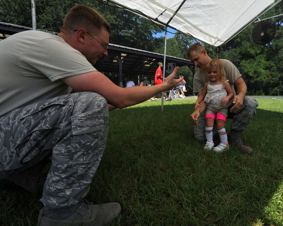 Mary-Kate Montrose holds on to her dad, Master Sgt. Mark Montrose for stability before walking into the arms of a family friend, Master Sgt. Ricky Smith at the Exceptional Family Members Fair Aug. 13, 2010. Mary-Kate attended the fair with her parents and two twin brothers. The fair encompassed activities and information booths for families to educate themselves on the resources and programs available to them both on and off base. Activities included a miniature pony for the children to pet, a dunk tank, face painting and golf. Sergeant Smith and Sergeant Montrose are both with the 628th Force Support Squadron. (U.S. Air Force Photo/Airman 1st Class Lauren Main)