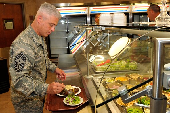 Chief Master Sgt. Robert Sealey, 21st Space Wing command chief, serves himself lunch at the Aragon dining facility Aug. 6 following a grand reopening celebration. The dining facility had been closed since April for a renovation project that including replacing the heating, ventilating and air conditioning unit, overhauling the restrooms and remodeling the dining area with a fresh, modern look. (U.S. Air Force photo/Rob Bussard)