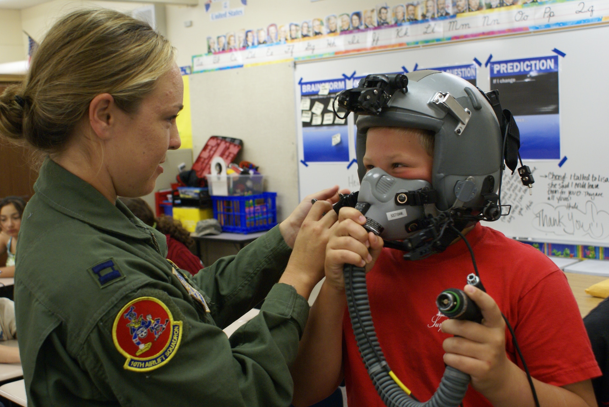 Capt. Emily Yturralde, 10th Airlift Squadron pilot assigned to Joint Base Lewis-McChord, Wash., helps a fifth grade student at Skyline Elementary School try on her helmet during a series of Tacoma elementary school visits Aug. 18. (U.S. Air Force Photo/Airman Leah Young)