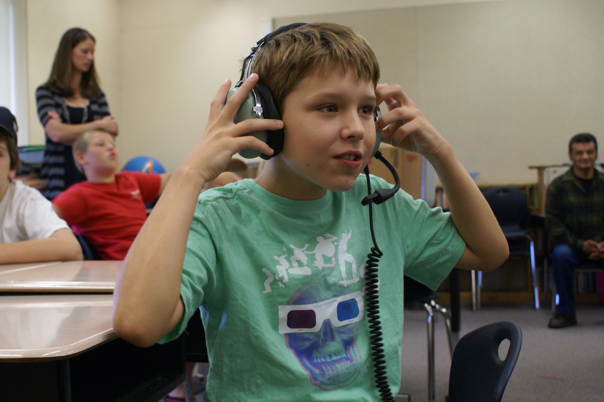 A fifth grade student at Skyline Elementary School wears a set of pilot's headphones during a series of Tacoma elementary school visits Aug. 18. (U.S. Air Force Photo/Amn Leah Young)