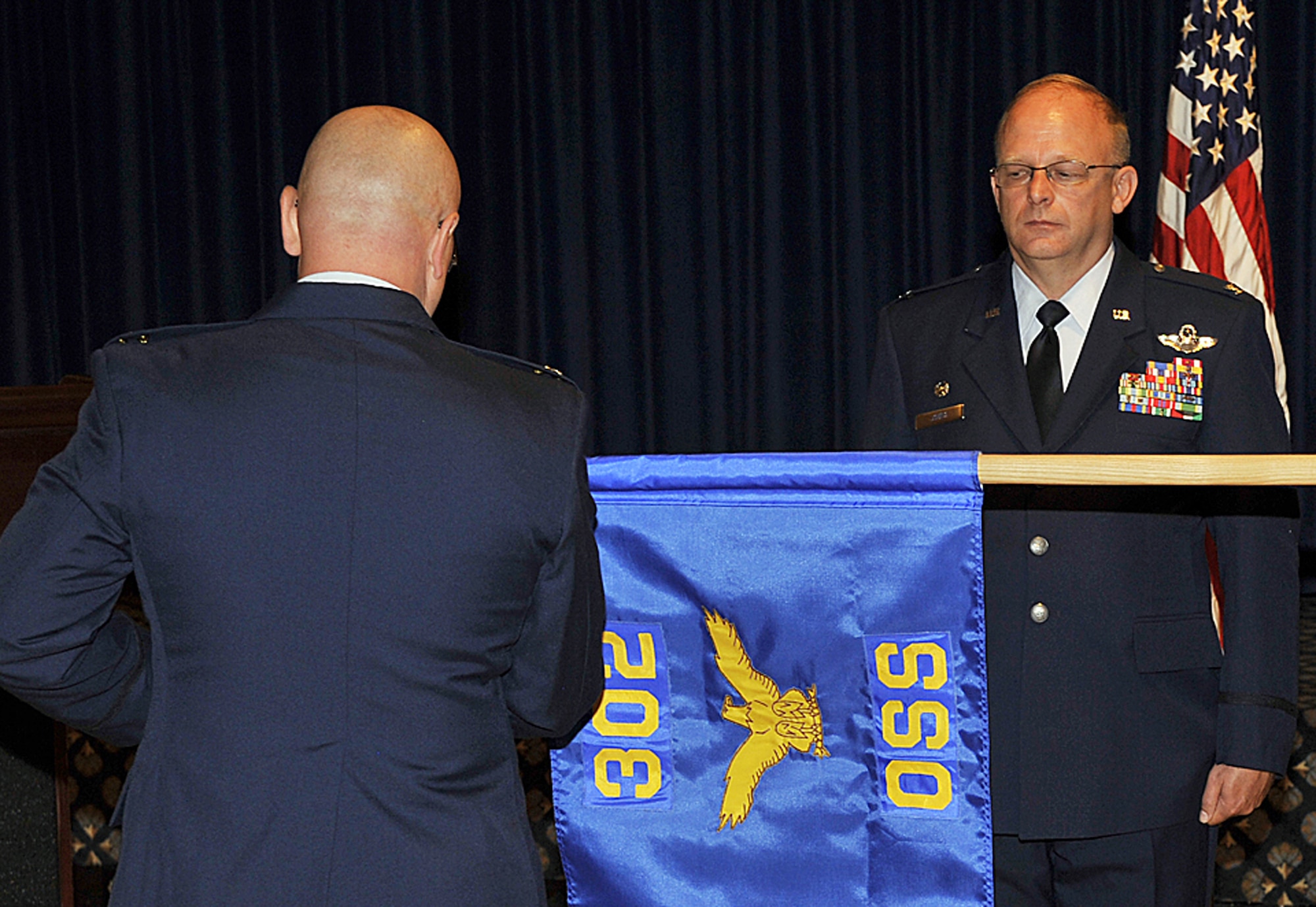 Col. Kurt D. Jones (right) watches as the 302nd Operations Support Squadron guidon is unveiled for the first time Aug. 8 at Peterson Air Force Base, Colo. The 302nd OSS, which was earlier inactivated as an operations support flight, was re-activated as a squadron to better reflect its growing mission. After the unit standup, Air Force Reservist Lt. Col. Jennie Johnson assumed command of the squadron. Colonel Jones, an Air Reserve Technician, is the commander of the 302nd Operations Group, a parent organization to the 302nd OSS. (U.S. Air Force photo/Larry Hulst)