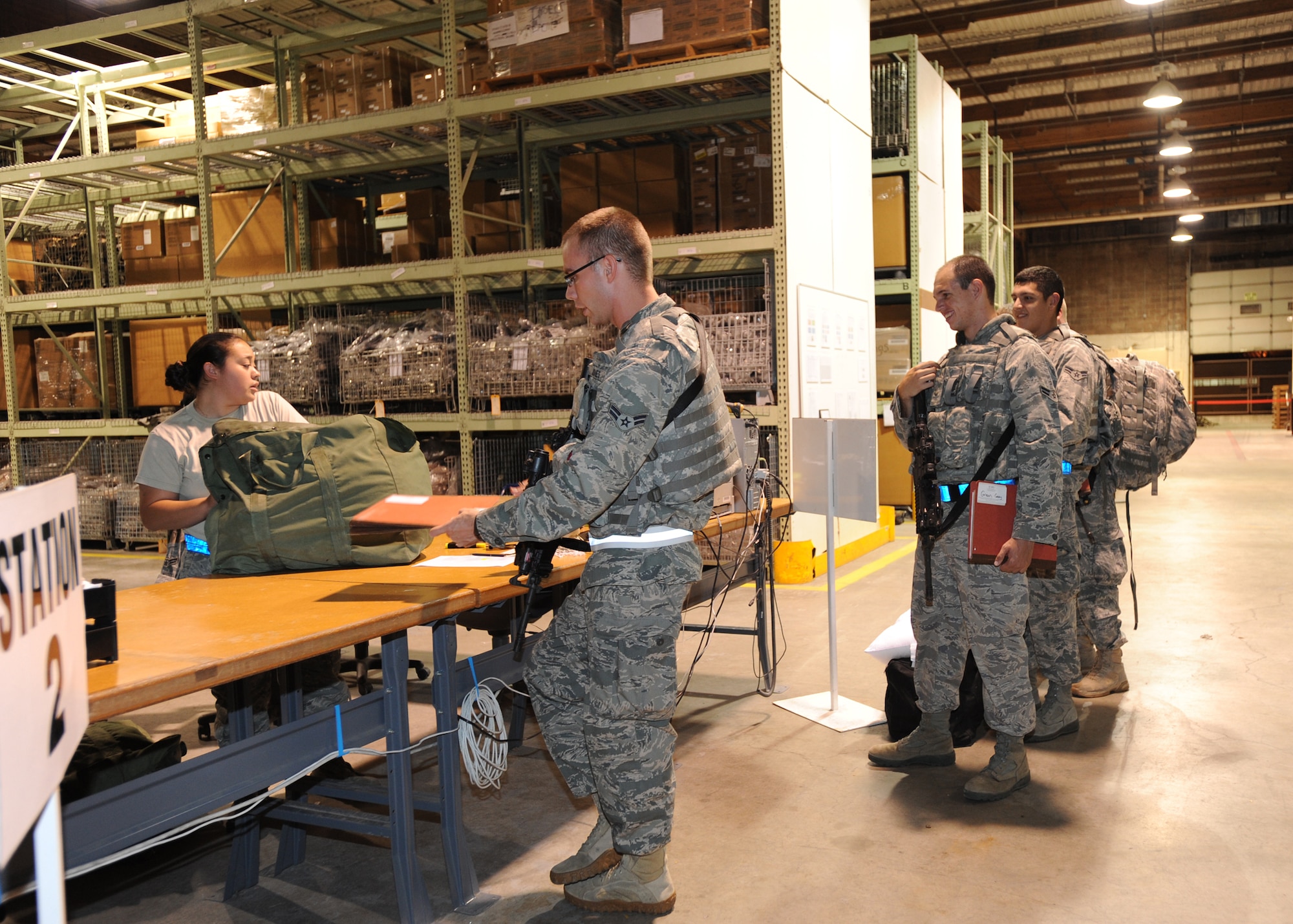 Airmen from the 22nd Security Forces Squadron make their first stop through the individual protective equipment issue section inside Building 1090 during an operational readiness exercise Aug. 16, 2010, McConnell Air Force Base, Kan.  McConnell Airmen practice mission support skills necessary to support Airmen deploying for real-world contingencies. (U.S. Air Force photo/Airman 1st Class Andrea Salazar)