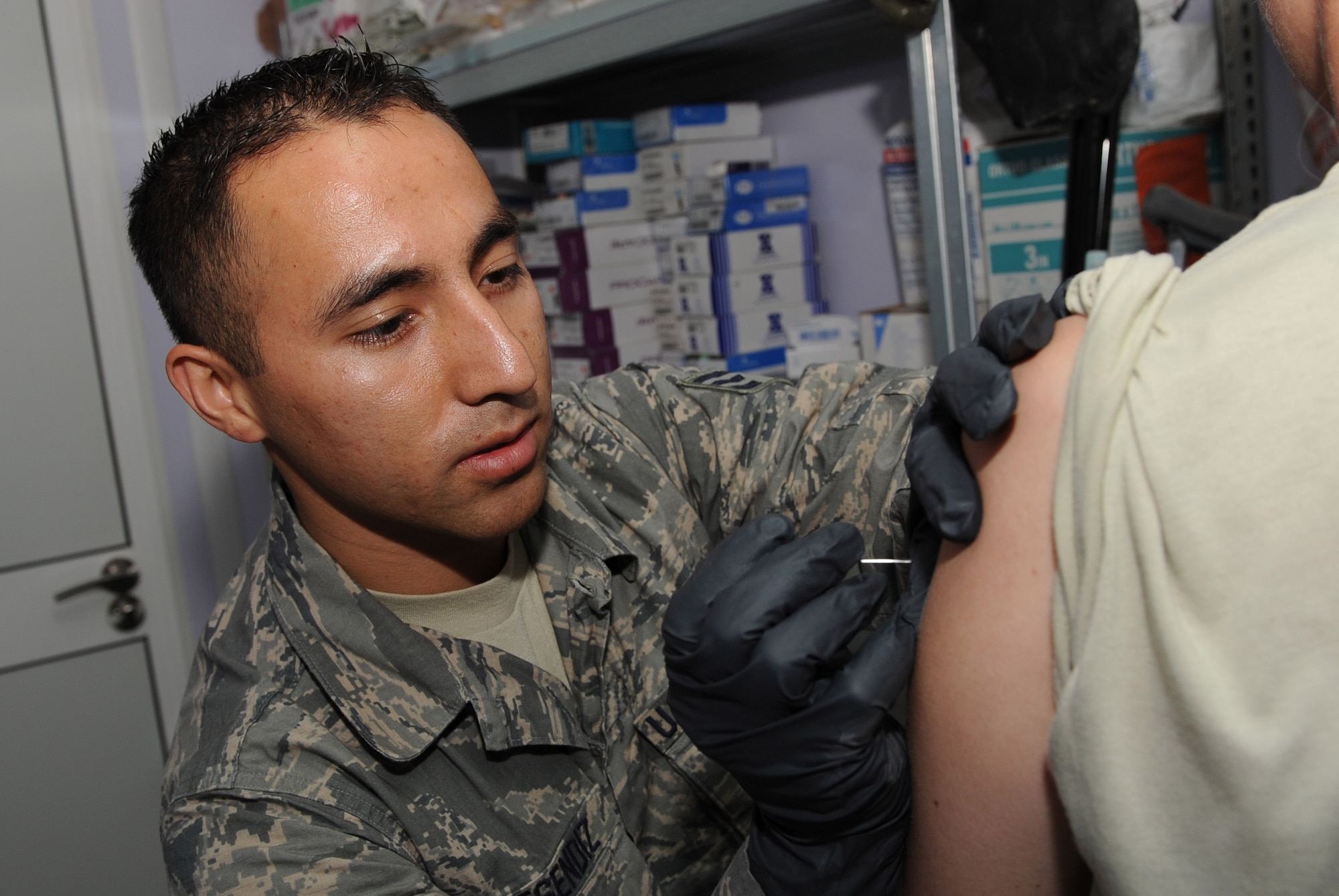 Senior Airman Rodrigo Resendiz administers the smallpox vaccination on a patient Aug. 18 at the 451st Air Expeditionary Wing Clinic. Airman Resendiz is a medical technician assigned to the 451st AEW Clinic, Kandahar Airfield, Afghanistan. (U.S. Air Force photo by Tech. Sgt. Chad Chisholm/Released)