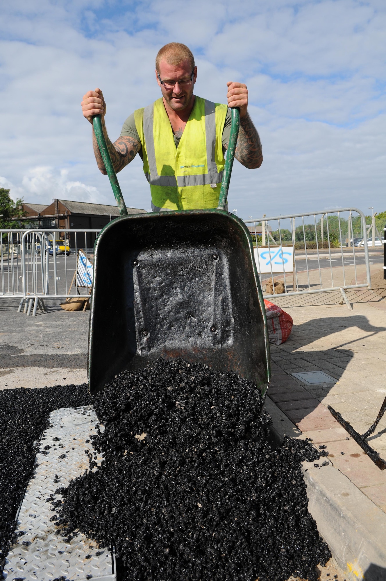 RAF MILDENHALL, England -- Simon Lomax, a local contractor, empties a wheelbarrow of fresh asphalt around newly installed bollards Aug. 18. The bollards being installed around the base are part of a new antiterrorism and force protection effort. (U.S. Air Force photo/Senior Airman Ethan Morgan)