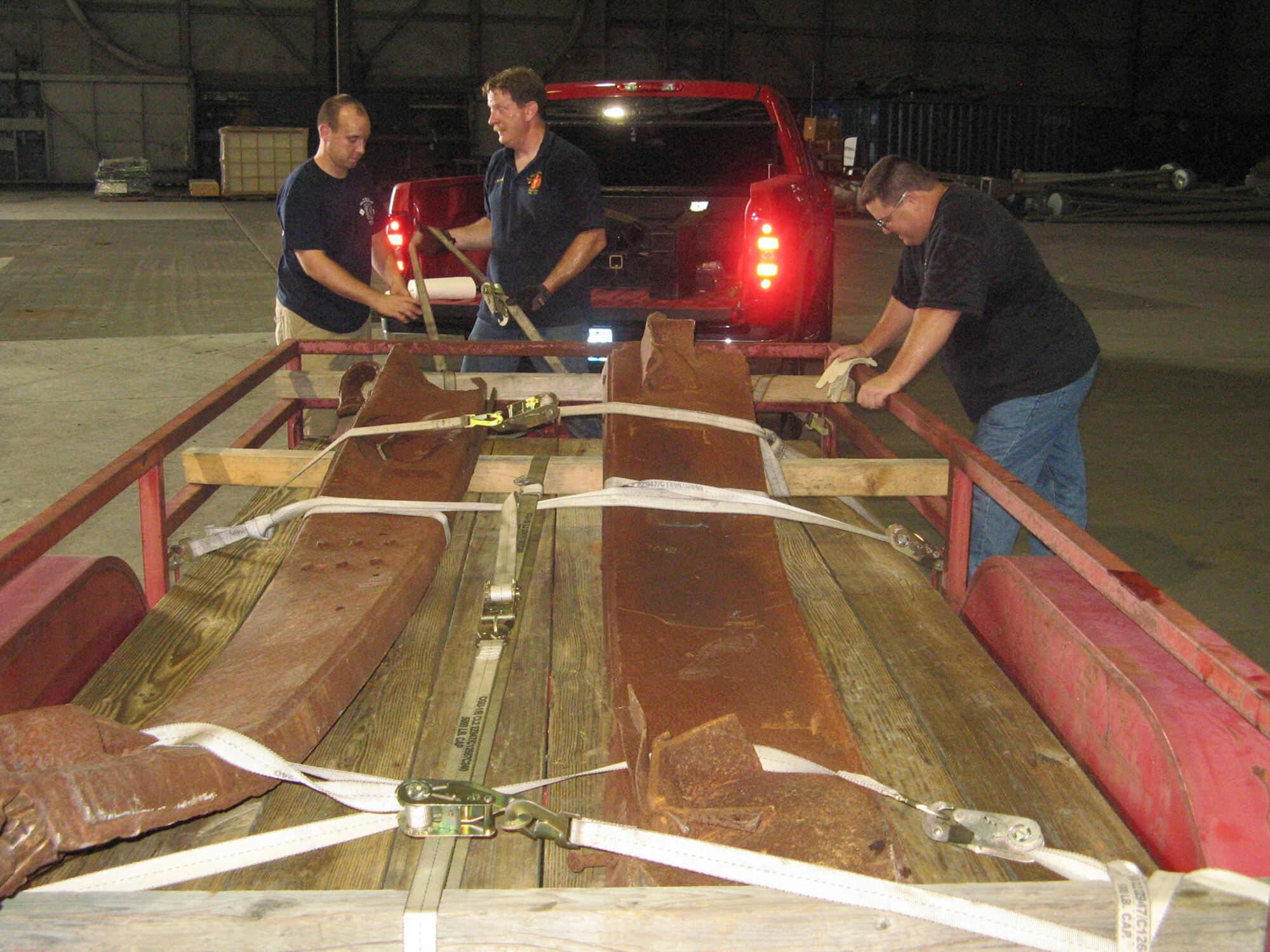 Airman William Watkinson, 436th Civil Engineers Squadron fire protection specialist, Jeff McCombs, 436th CES lead firefighter, and Dale Driscoll, 436th CES lead dispatcher, secure steel onto a trailer to take back to Dover Air Force Base Aug. 10, 2010. The steel will be used to build a memorial in remembrance of the World Trade Center attack Sept. 11, 2001. (U.S. Air Force photo courtesy photo/Released)