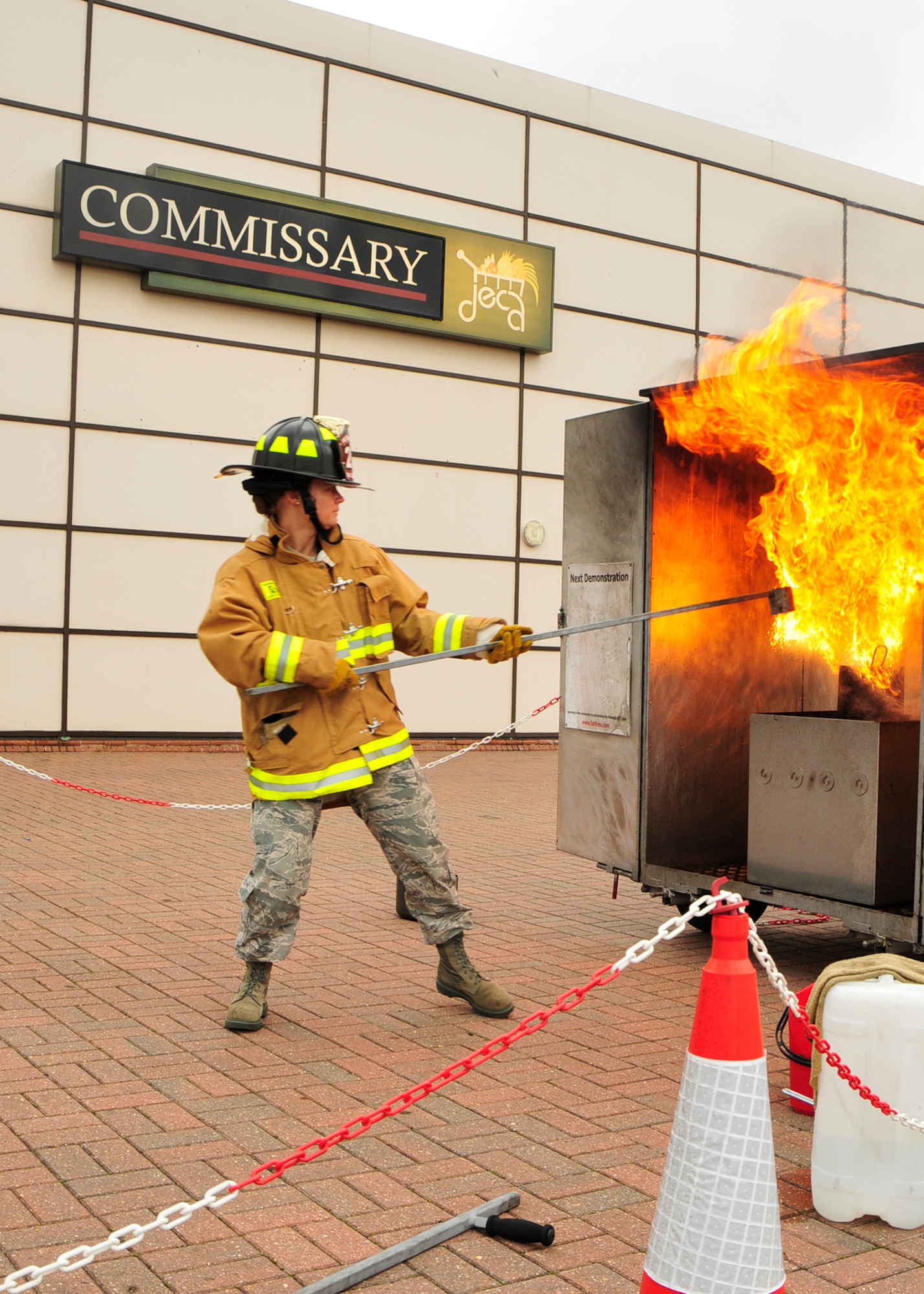 Tech. Sgt. Carrie Frederickson, 48th Civil Engineer Squadron fire inspector, demonstrates how not to put out a grease fire by pouring a cup of water onto the flaming pot during a fire safety demonstration outside the RAF Lakenheath base commissary Aug. 13. Grease fires should be put out by covering the pot with a damp cloth or sliding a pan over the top of the pot. Water will make grease fires larger, potentially causing a house fire. (U.S. Air Force photo/Airman 1st Class Tiffany Deuel)