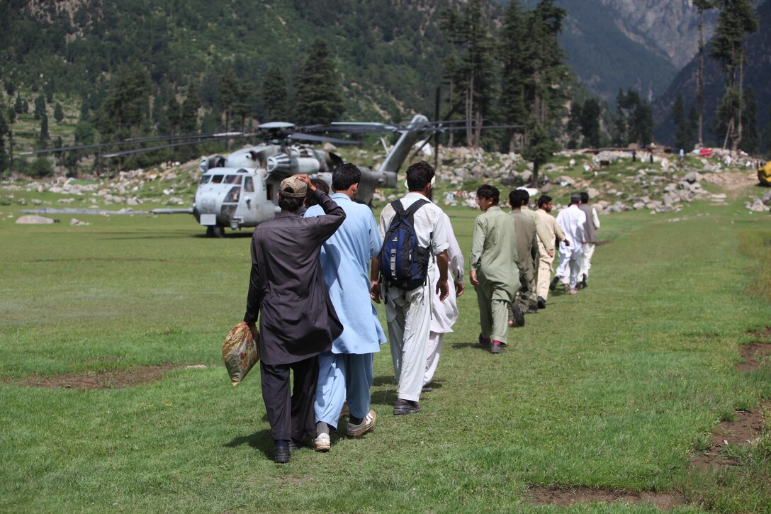Pakistani civilians walk to a CH-53E Super Stallion helicopter during humanitarian relief efforts in the Khyber-Pakhtunkhwa province, Pakistan(formerly known as the Northwest Frontier province, Pakistan).