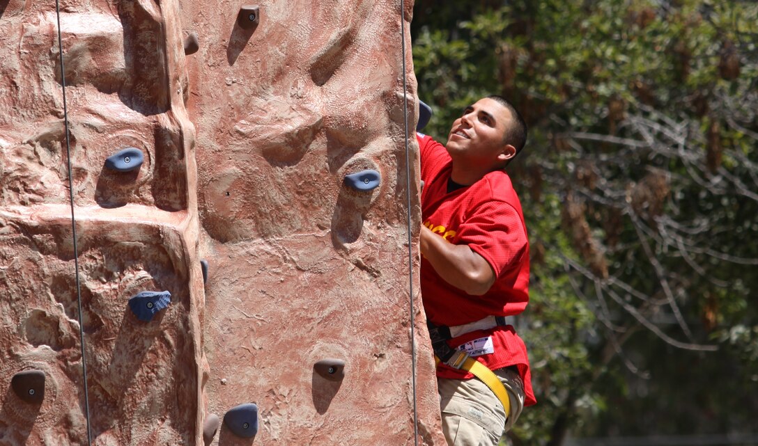 Cpl. Adam Barker, patient, Wounded Warrior Battalion West, Camp Pendleton, climbs a rock-wall during the unit’s family day festival at Lake O’Neil, Aug. 19. Throughout the event, more than 200 children and adults participated in numerous physical activities, such as rock-wall climbing, foot races and jumping around in bounce houses. Attendees also enjoyed lots of free catered food.::r::::n::