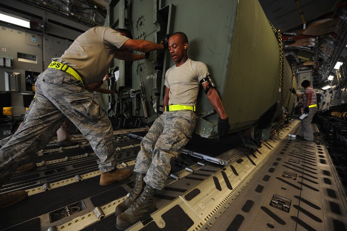 Senior Airman Marvin Richardson, right, and Master Sgt. Randall Pickenpaugh muscle up to the weight of the Improved Float Bridge system shipped from Joint Base Charleston, S.C., Aug. 18, 2010. Approximately 40 sections of bridge were delivered to the 437th Aerial Port Squadron from Missouri, along with three boats which act as waterborne mooring vehicles. Bridge shipments are expected to continue until the end of the month, supplementing a larger sealift operation. Both Sergeant Pickenpaugh and Airman Richardson are with the 437 APS. (U.S. Air Force photo/Airman 1st Class Lauren Main)