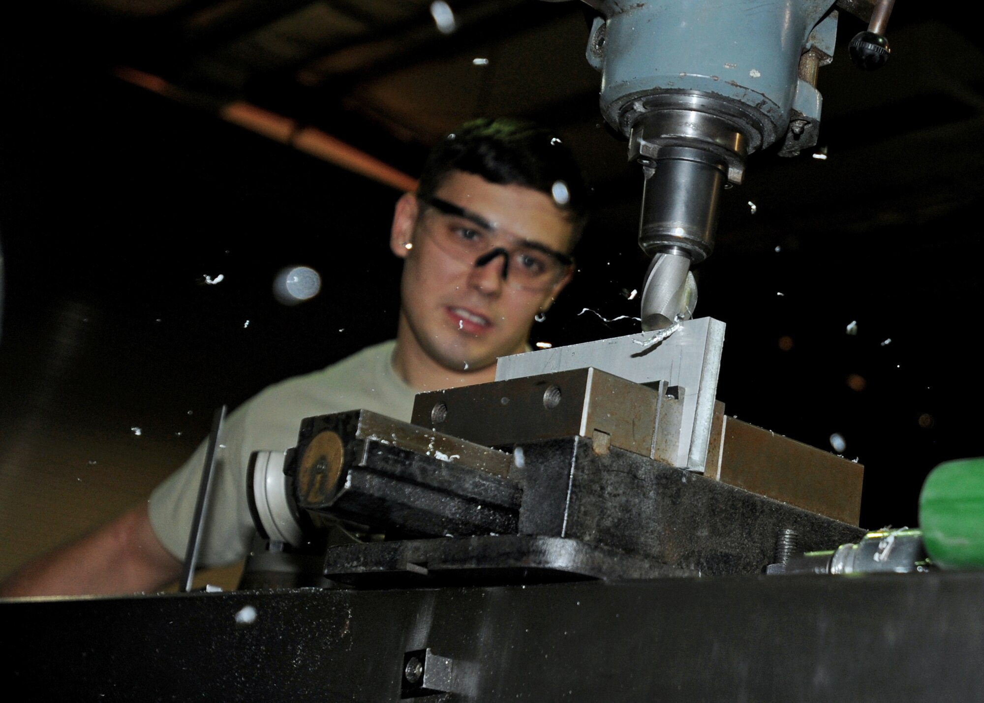 SOUTHWEST ASIA – Metal pieces fly as Airman 1st Class Phillip Jackson, an aircraft metals technology journeyman from the 386th Expeditionary Maintenance Squadron’s Combat Metals Flight, feeds a part into the mill cutter during the process of making a C-12 rudder alignment fixture here Aug. 17, 2010. The flight can repair metal parts for U.S. Air Force, U.S. Army and host-nation aircraft across CENTCOM by welding, cutting, bending, and shaping components from a single block of metal. (U.S. Air Force photo by Senior Airman Laura Turner)