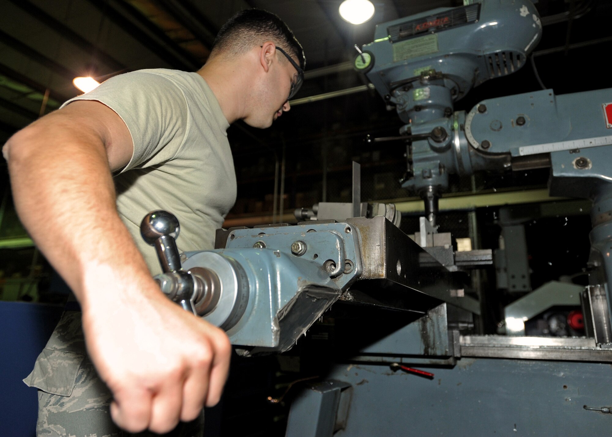 SOUTHWEST ASIA - Airman 1st Class Phillip Jackson, an aircraft metals technology journeyman from the 386th Expeditionary Maintenance Squadron’s Combat Metals Flight, feeds a part into the cutter on a mill to make a C-12 rudder alignment fixture here Aug. 17, 2010. The nine-man flight includes specialists from the aircraft metals technology and aircraft structural maintenance career fields. Aircraft metals technologists manipulate thicker portions of metal into fine-tuned parts, and sheet metal technicians work with thinner pieces of metal like the outer skins of aircraft or precision bent tubing for hydraulic and fuel systems. (U.S. Air Force photo by Senior Airman Laura Turner)