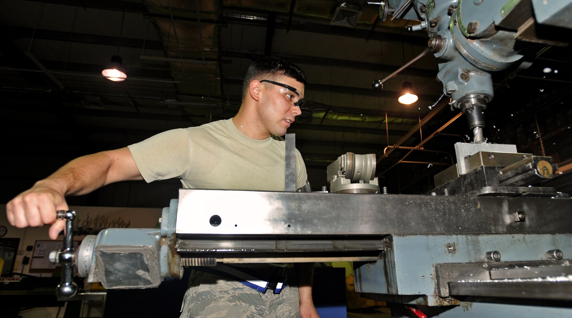 SOUTHWEST ASIA - Airman 1st Class Phillip Jackson, an aircraft metals technology journeyman from the 386th Expeditionary Maintenance Squadron, feeds a part into the cutter on a mill to fabricate a C-12 rudder alignment fixture here Aug. 17, 2010. The mill is used to make necessary repairs through manual manipulation and the parts are hand-crafted to the finest detail. (U.S. Air Force photo by Senior Airman Laura Turner)
