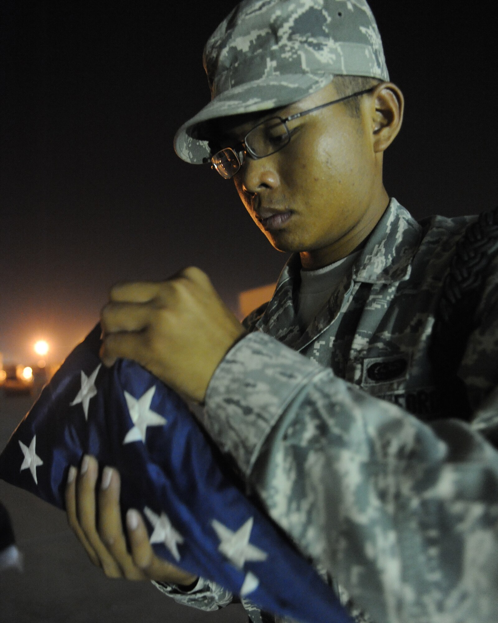 Airman 1st Class Timothy Nguyen learns how to fold up a U.S. Flag to honor fallen military members at an undisclosed location in Southwest Asia August 3. Airman Nguyen is a civil engineer escort with the 379th Expeditionary Civil Engineer Squadron and is deployed from Minot AFB, ND. (U.S. Air Force photo/Senior Airman Katie Gieratz)