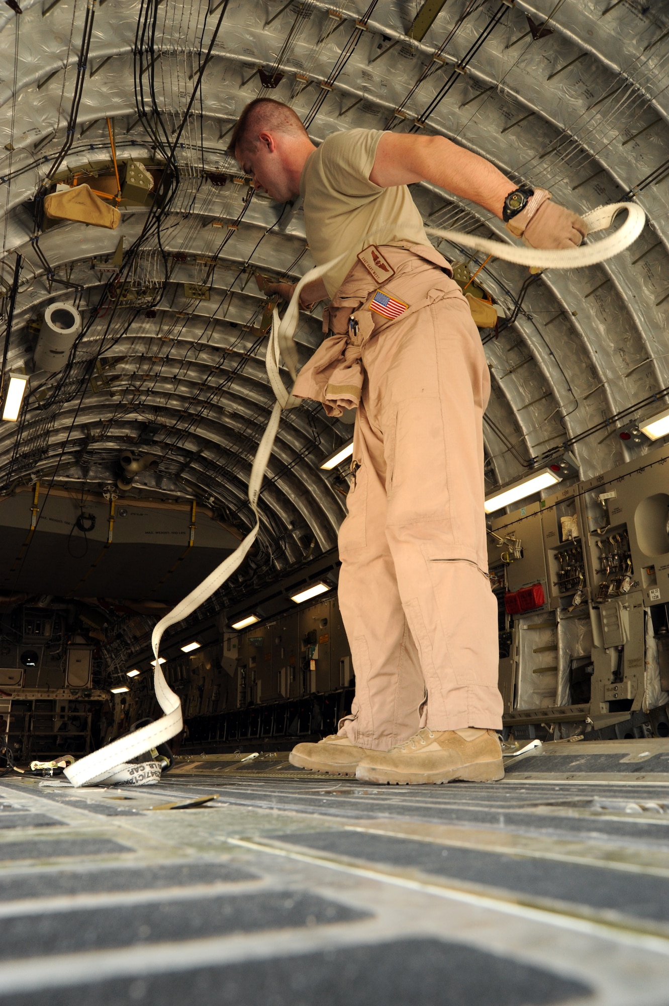 Staff Sgt. Gary West, 817th Expeditionary Airlift Squadron instructor airdrop loadmaster, unravels cargo straps in preparing the cargo area of a C-17 Globemaster III at an undisclosed location in Southwest Asia to hold bundles for an airdrop Aug. 13. The drop was part of Operation Everest, a week-long effort delivering more than 1,192,000 pounds of supplies and equipment to forward operating bases across the area of responsibility. (U.S. Air Force photo/Staff Sgt. Tim Jenkins)