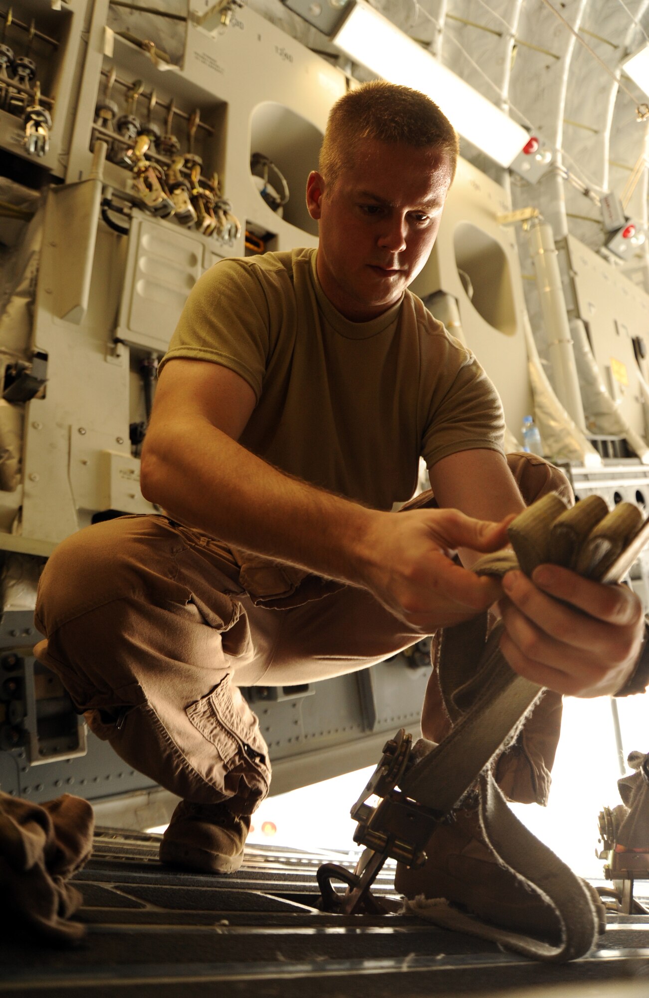 Staff Sgt. Gary West, 817th Expeditionary Airlift Squadron instructor airdrop loadmaster, secures cargo straps in a C-17 Globemaster III at an undisclosed location in Southwest Asia prior to an airdrop Aug. 13. The drop was part of Operation Everest, a week-long effort to fully exercise the C-17 theater airdrop capability . (U.S. Air Force photo/Staff Sgt. Tim Jenkins)