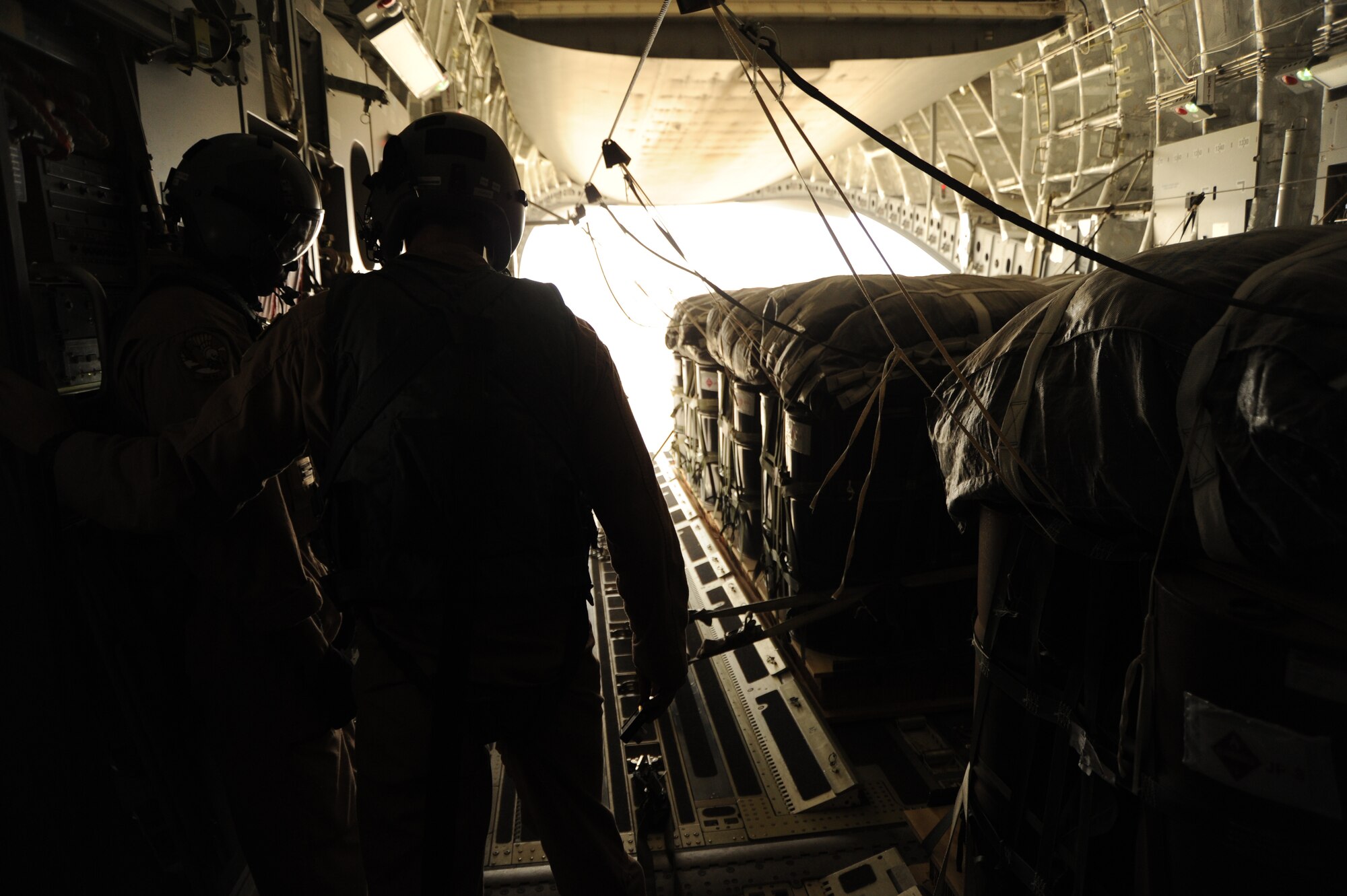 1st Lt. Daniel Hartung and Staff Sgt. Hardia Madden, 816th Expeditionary Airlift Squadron, watch as bundles of JP-8 fuel begin to exit a C-17 Globemaster III over a drop zone during an airdrop mission Aug. 13. (U.S. Air Force photo/Staff Sgt. Tim Jenkins)
