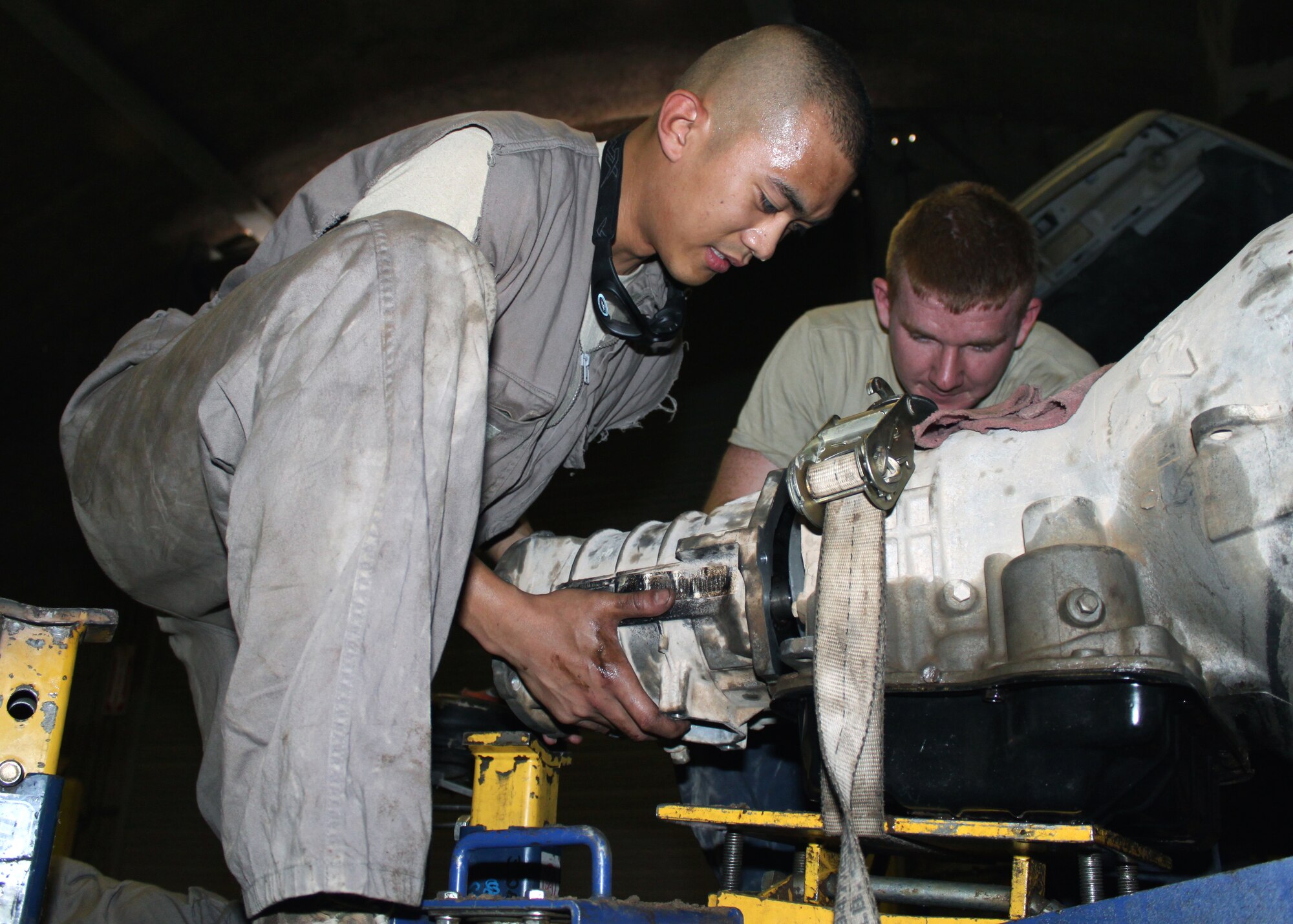 Staff Sgt. Jeffery Ramirez (left) and Senior Airman Jeffrey Griffin, 332nd Expeditionary Logistics Readiness Squadron Vehicle Maintenance Flight multi-purpose mechanics, put a transmission together after repairing the park paw rod on a tug vehicle Aug. 10, 2010, Joint Base Balad, Iraq.  Airmen in the 332 ELRS aren’t afraid to get dirty when it comes to repairing vehicles needed for the mission. Sergeant Ramirez, a native of San Jose, Calif., is deployed from the 349th Logistics Readiness Flight, Travis Air Force Base, Calif.; Airman Griffin, a native of Chapin, S.C., is deployed from the 628th Logistics Readiness Squadron, Joint Base Charleston, S.C. (U.S. Air Force photo/Staff Sgt. Stacy Fowler)