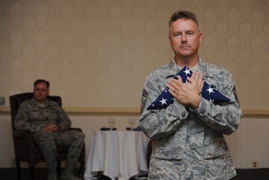 Command Chief Master Sgt. Mike Ivey holds the American Flag close, following the flag presentation by Command Chief Master Sgt. Terrence Greene during Chief Ivey's official retirement ceremondy which was presided over by Col. John Wood at the Charleston Club Aug. 20, 2010. Chief Ivey will retire in November after 23 years of service to the United States Air Force. Chief Ivey began his career as an Airman Basic on April 22, 1987 and proceeded to go above and beyond the call of duty, achieving the highest enlisted rank in the Air Force.  Col. Wood is the commander of the 437th Airlift Wing, Chief Greene is the command chief of the 437 AW and Chief Ivey will retire as the command chief of the 628th Air Base Wing. (U.S. Air Force Photo/Airman 1st Class Lauren Main)