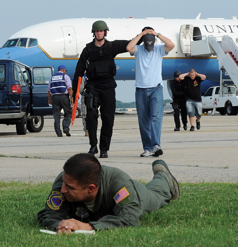 Senior Airman Benjamin Lee, 316th Security Forces Squadron emergency service team member and military working dog handler, escorts players in an aircraft hijacking exercise at Joint Base Andrews Tuesday. The 89th Air Wing and 316th Security Forces Squadron worked together to conduct the hostage negotiations. (U.S. Air Force photo/ Bobby Jones)